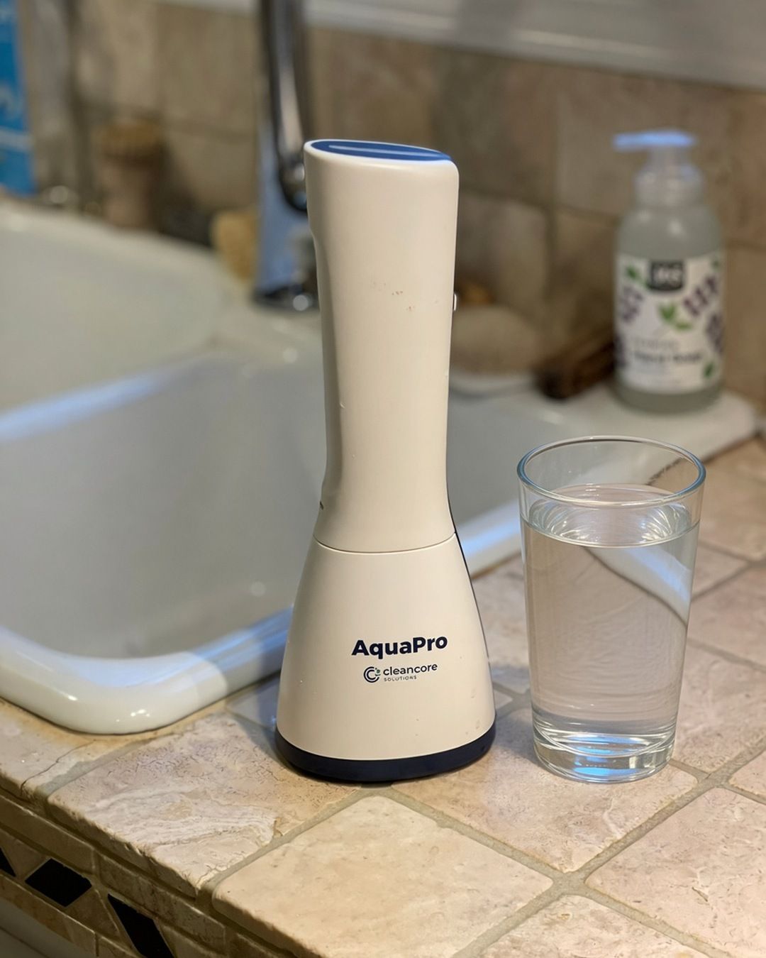 AquaPro beside a glass of tap water on a kitchen counter
